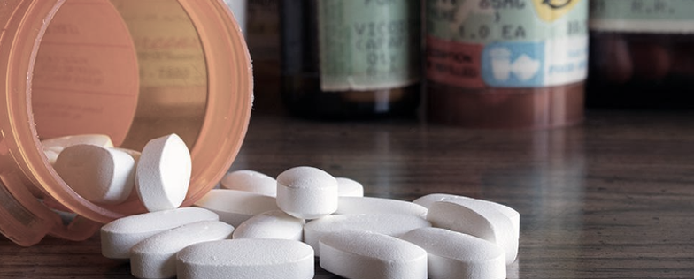 Prescription tablets spilling from an open bottle.